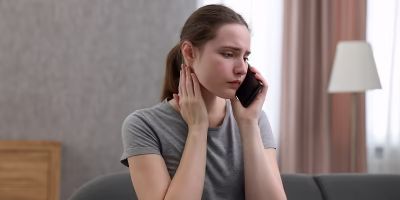 Crisis-Support Young woman looking distressed while talking on the phone at home