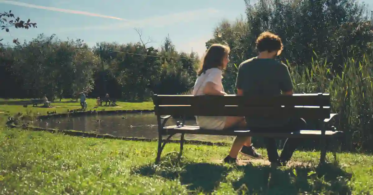 Two people sitting apart on a park bench, illustrating loneliness and the need for social connection